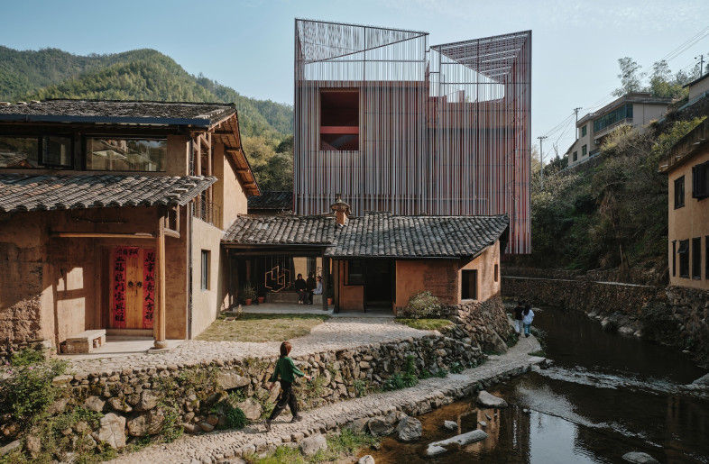 Instead of pretending a 1990s concrete box seamlessly blends into centuries-old vernacular architecture, Team_Bldg wraps it in a striking lattice of red-and-white aluminium tubes. - Jonathan Leijonhufvud