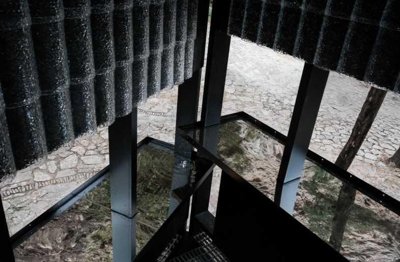 Two mirrored stainless-steel pools run along two sides of the pavilion. - Aptdotapt