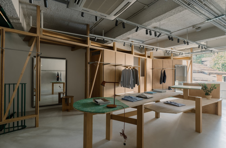 White track lighting stretches beneath russet-toned beams. - Wen Studio