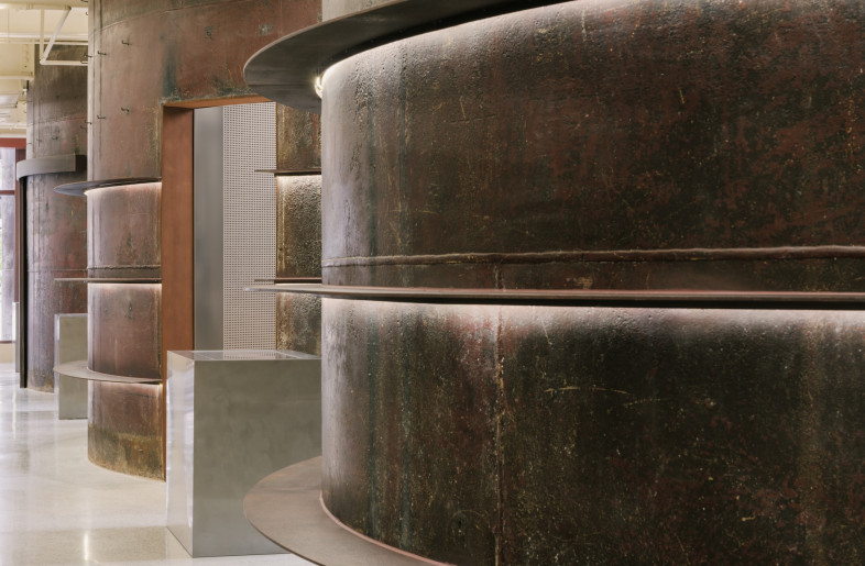 The dramatic presence of oxidized tanks, set against a minimalist but modular material palette, sets the tone for a space that encourages repeated engagement. - Wen Studio