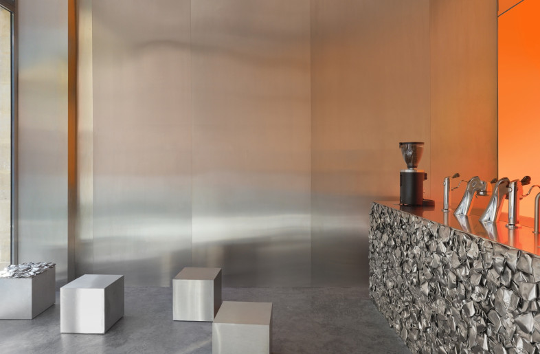 The central counter – where baristas brew and customers order – is crafted from stainless steel moulded in a compressed coffee cup silhouette. - Courtesy of Crosby Studios