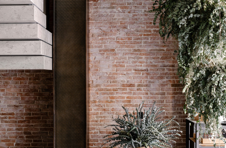 A floating staircase sits alongside brick-clad walls to welcome visitors into the space. - Photograph by Lit Ma
