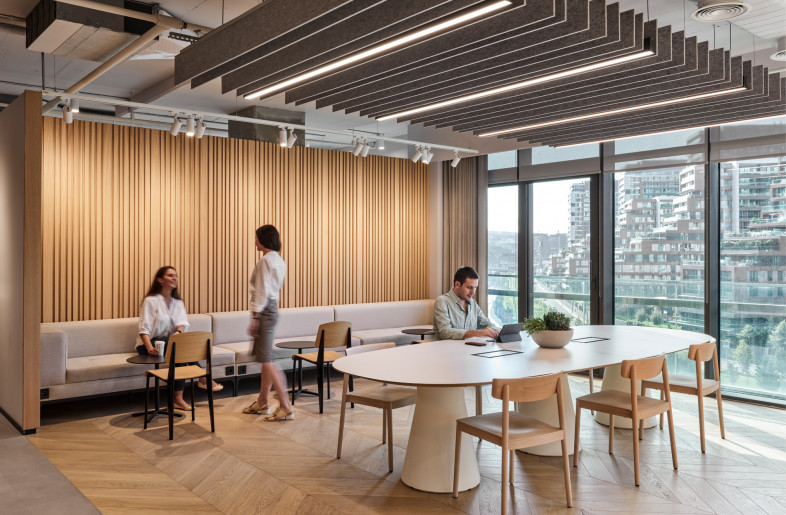 Suspened acoustical panels are used above the table in the social area. The layout of this spaces varies for differenet floors and deparrtments. Here a soft seating was added along the wood claded wall. - Photo by Ibrahim Ozbunar https://www.ibrahimozbunar.com/