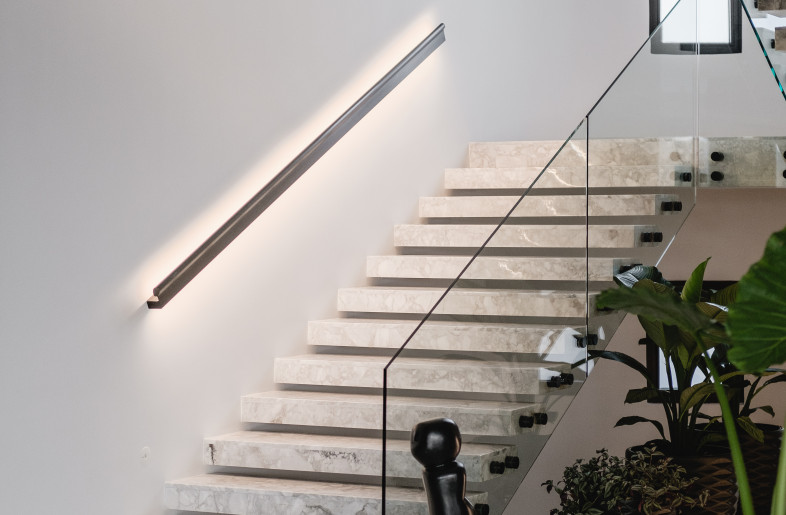 Light grey marble complimented by sleek black accents creating a bright stairway leading to the main living floor. - Nour El Refai (Photography)