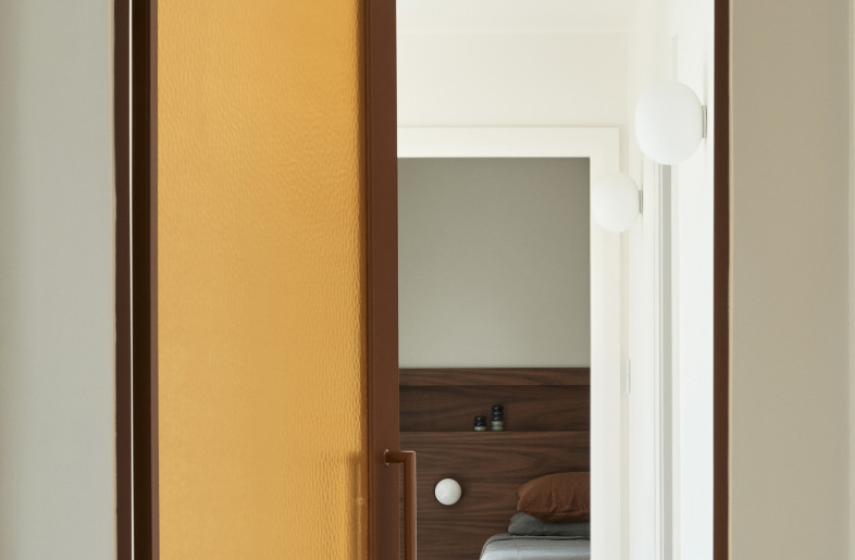 The arched amber rippled glass door brings a moment of playfulness to the design. - Photography: Damian Bennett
