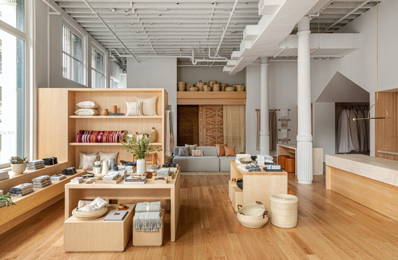 Opposite the window walls, large white planes and casework with intricate wood slat detailing frame the collection of natural fabrics, rugs, baskets and pillows made worldwide by artisans. - Sean Litchfield