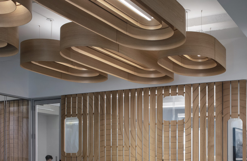 A custom ceiling was designed as floating canopy of wood and light; experimentation with molded wood veneer flitches were done to create concentric forms of varying depths and interior volume. The result is a dynamic installation that brings texture and scale to the space while allowing the ripples to float overhead, almost as if one were under water. - Paul Warchol