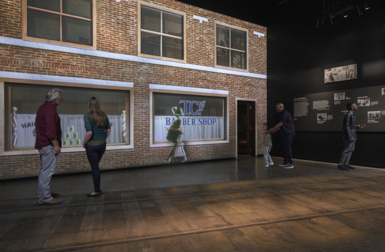 The Greenwood Spirit: Visitors cross the train tracks to meet district founders and learn about Greenwood’s early placemaking and economic rise. A projection mapped film shows the building of Greenwood brick by brick. - Local Projects/ Mel Willis