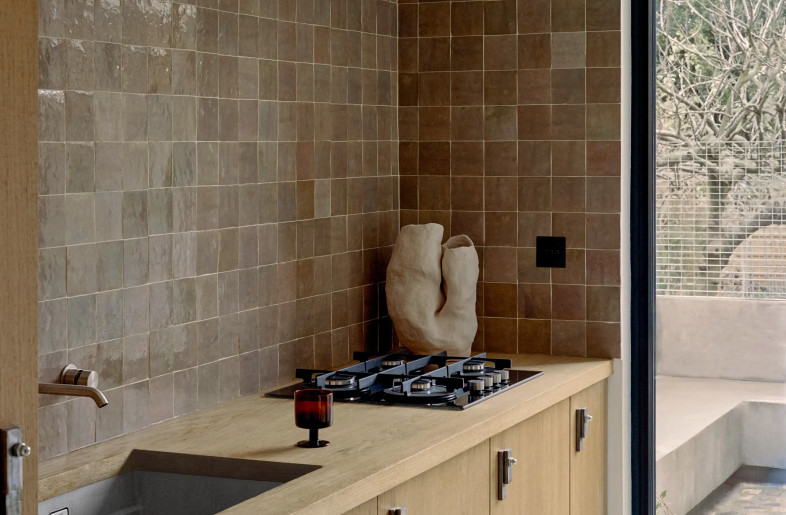 an elegant kitchen with clear rough-sawn oak cabinets, artisanal backsplash and a large contemporary glass sliding door leading to a garden - Christophe Coënon
