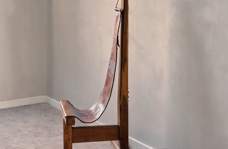 contemplative wood and leather chair by Dominique Zimbacca in a shadowy, off-white space - Christophe Coënon