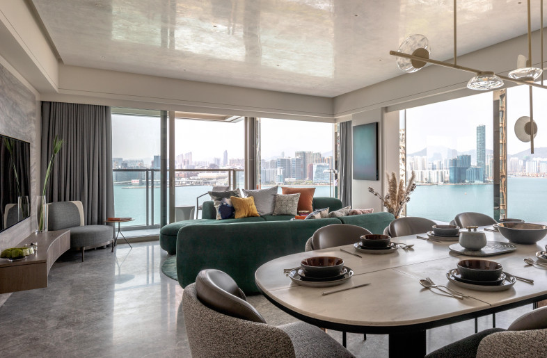 In the living room, expansive floor-to-ceiling windows open to bright panoramic views of the harbour. Mullions are wrapped in chrome with a sleek mirror finish making them appear almost invisible, dissolving the barrier between interior and exterior. To underscore this effect and bring the outdoors inside, a shimmering grey-blue Venetian stucco ceiling with an ombre pattern acts like a seamless extension of the sky. Similarly toned marble floors and a silver travertine feature wall have subtle blue accents. Seen together, these elements call to mind the glistening surface of the sea. - Mr. Edmon Leong
