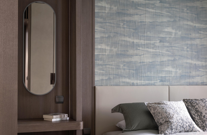 The water-inspired narrative continues in the elegant master suite. Woven blue wallpaper from Armani Casa conjures a calming seascape above the leather bed which is dressed with a luxurious silk duvet and linens by Frette. - Mr. Edmon Leong