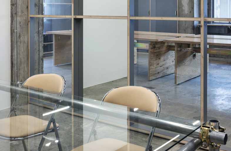 The meeting room is furnished with a glass table on legs made of steel pipes for scaffolding and leather upholstered chairs by Hender Scheme. - Kenta Hasegawa