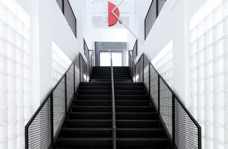 A black steel staircase is inserted under the 12-meter-high original roof in a former glass-making. - COORDINATION ASIA