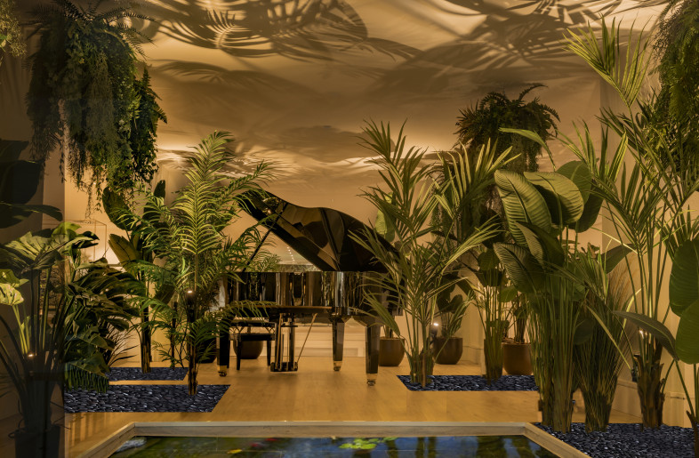 A grand piano is camouflaged among lush vegetation. - Jose Salto